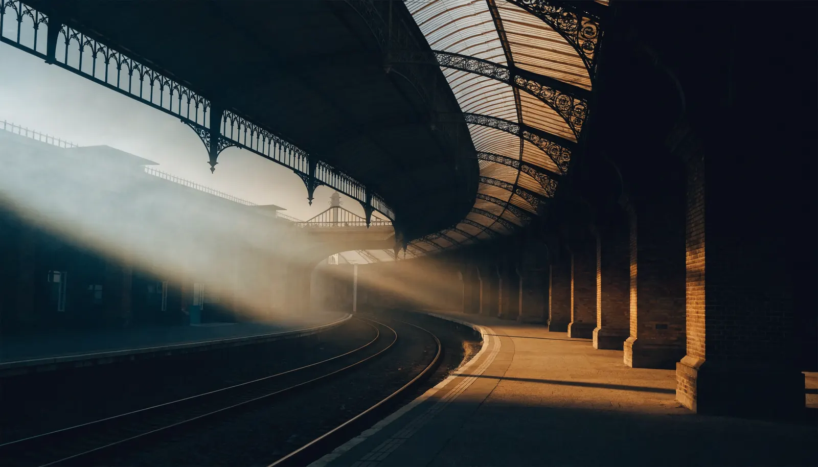 Quai de gare désert sous une verrière ancienne, lumière du matin